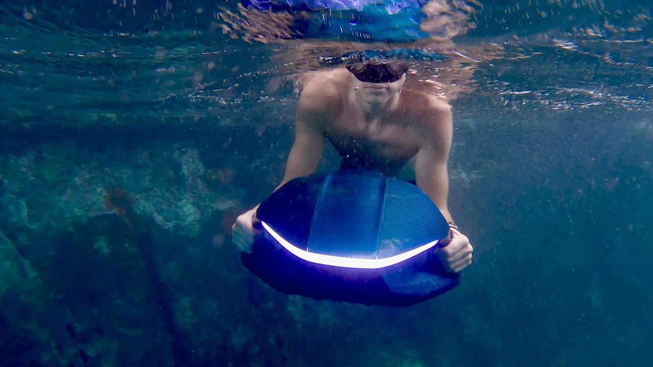 Person swimming with a sea scooter in turquoise ocean water